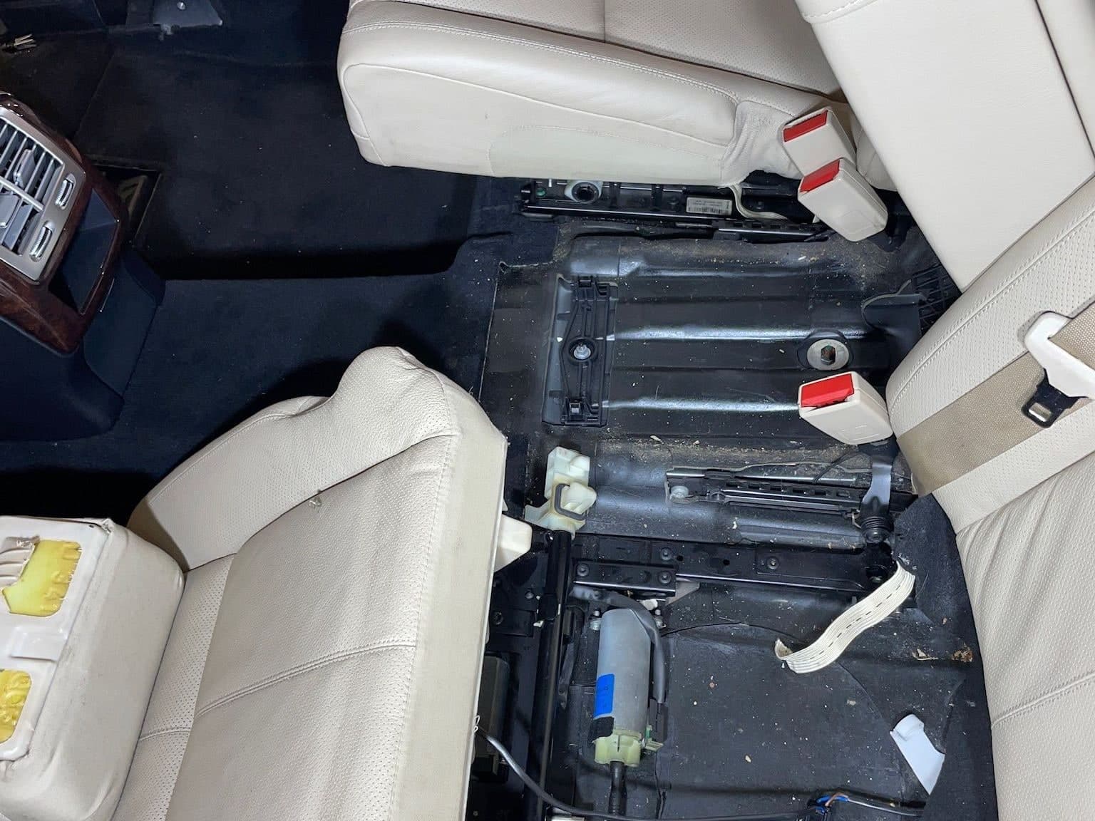 Mercedes S-Class with the front seats removed — seat rails and floor with debris under the seats