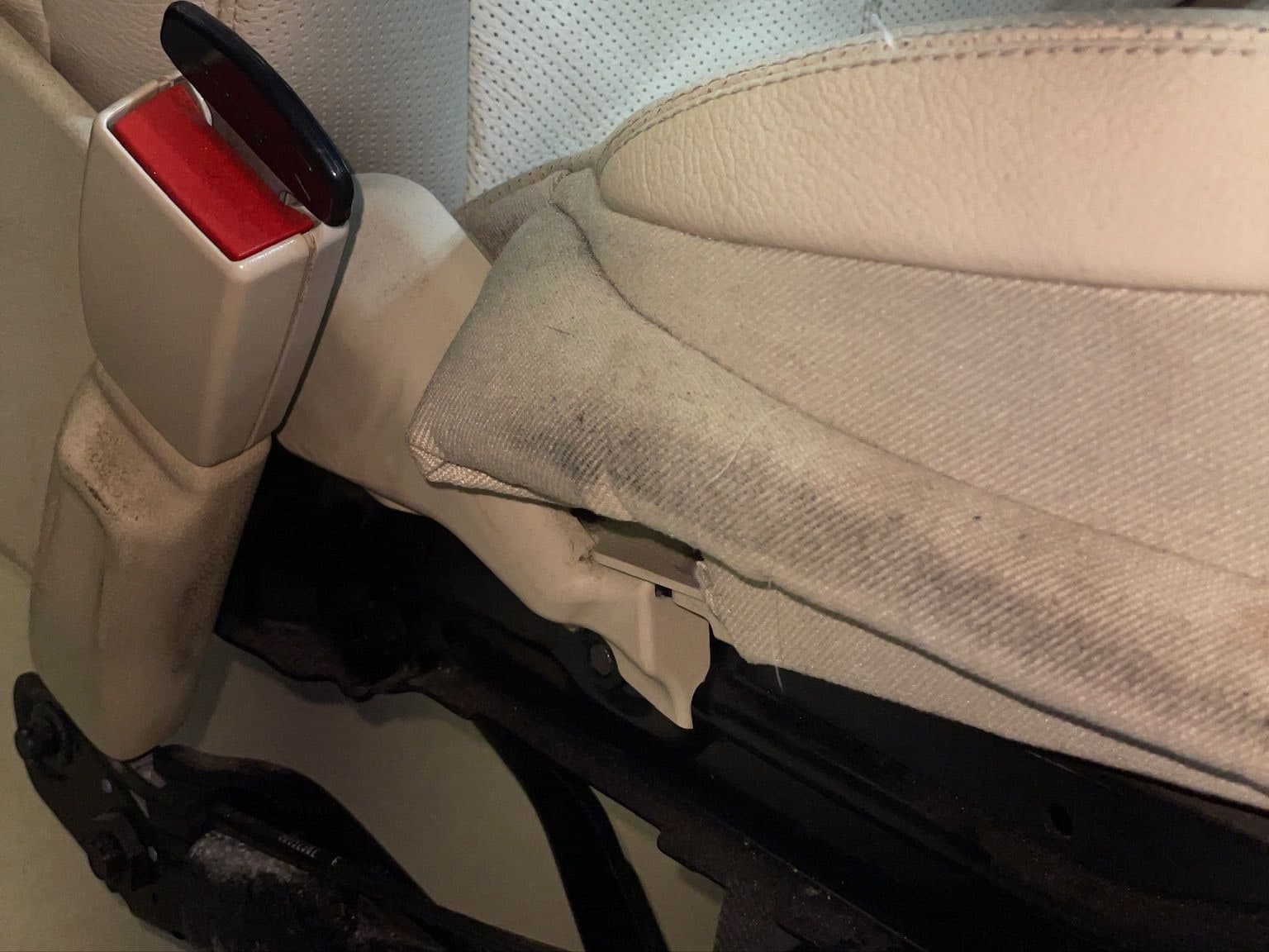 Side bolster of a light leather front seat with ground-in dirt, before cleaning
